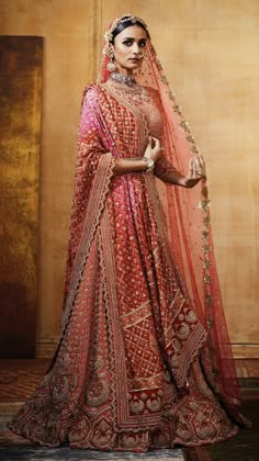 a woman in a red bridal gown with an elaborate veil on her head and shoulders