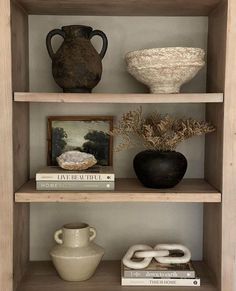 three shelves with vases and books on them