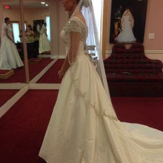 a woman in a wedding dress looking at herself in the mirror while she is getting ready to walk down the aisle