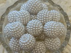 a glass bowl filled with white beads on top of a tablecloth covered floor next to a wall