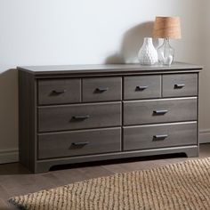 a large gray dresser sitting in a room next to a lamp on top of a rug