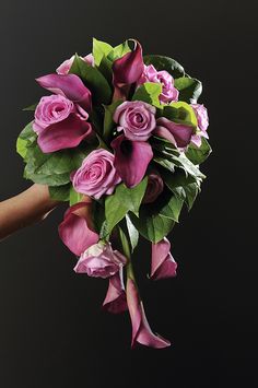 a bouquet of pink roses being held by a person's hand on a black background