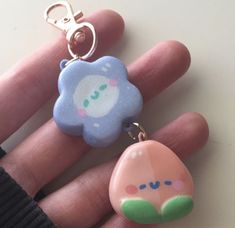 a hand holding two different shaped items on it's thumb and one has a keychain attached to it