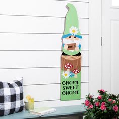 a wooden gnome sign sitting on top of a table next to a potted plant