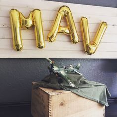 an air plane sitting on top of a wooden box next to some gold foil balloons