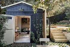 a small shed with an open door on the side and stairs leading up to it