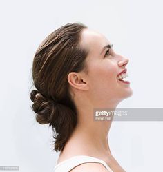 a woman with her hair in a low bun smiling and looking up at something off to the side