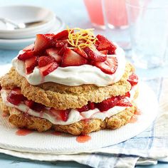 strawberry shortcakes stacked on top of each other with whipped cream and strawberries