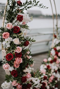 flowers and greenery are arranged on the side of a boat dock for an outdoor ceremony