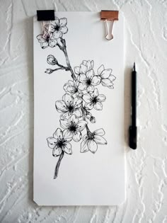 a piece of paper with flowers drawn on it next to a pen and ink drawing