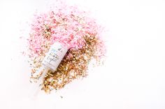 pink and gold glitter sprinkles with a tube on the top, against a white background