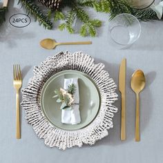 a place setting with silverware, pine cones and greenery on the table top