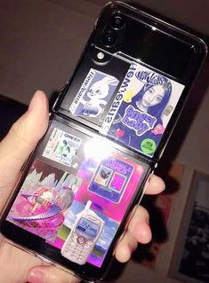 a person holding up a cell phone with stickers on the back of it's screen