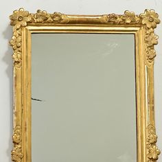 an ornate gold framed mirror against a white wall