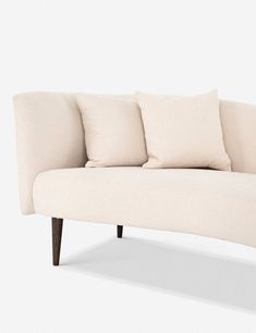 a white couch with four pillows on it's back and two arms, sitting against a wall