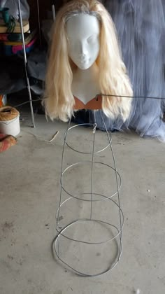 a white mannequin head sitting on top of a metal wire stand with hair hanging from it's sides