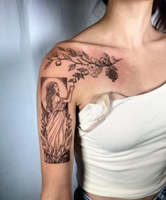 a woman with a cross and flowers tattoo on her left upper arm, wearing a white top