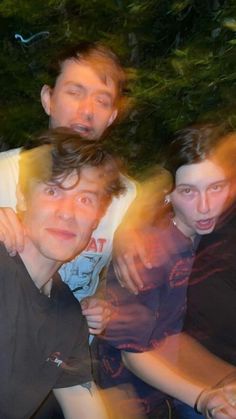 three men are posing for the camera with their arms around each other and one man has his eyes closed