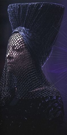 a woman with a netted hat on top of her head and purple lights behind her