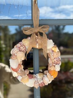 a wreath hanging on the side of a window with seashells and sand dollars