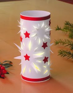 a red and white vase sitting on top of a wooden table next to a plant