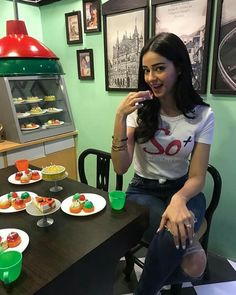 a woman sitting at a table with plates of food on the table and pastries in front of her