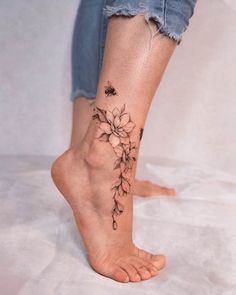 a woman's foot with a flower tattoo on her left side and the bottom part of her leg