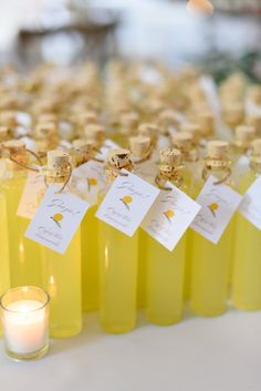 several bottles of yellow liquid with small tags on them next to a candle and some candles