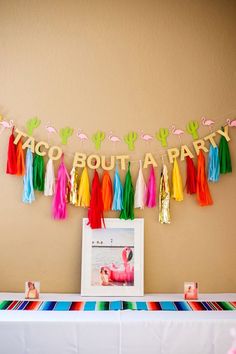 tassels and streamers are hanging from the wall above a table with a photo on it