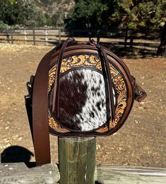 Gorgeous canteen style bag.  Hand tooled floral design surrounds this amazing speckled longhorn cowhide inlay. Piping on front and back edges.  Fabric lined inside.  One outside pocket.  40 inch strap with hand rubbed edges and stainless hardware.  Flat bottom so it stands up on its own.  Hidden zipper top closer with double zipper pulls and stylish bleed knot tassels. This amazing bag measures 10 inches tall by 11 inches across and 3 inches wide. You will be the envy of all your friends with th Leather Canteen, Zipper Top, Zipper Pulls, 11 Inches, Hidden Zipper, Western Fashion, Cross Body Handbags, Purses And Handbags, Piping