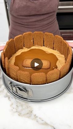 a cake in a pan on top of a counter with a person standing next to it