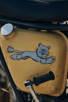 an old yellow motorcycle with a cat painted on the side