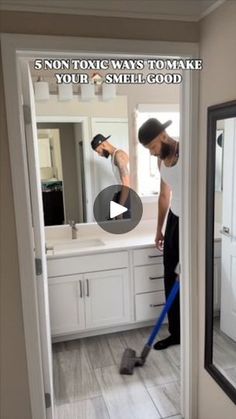 a man is using a vacuum to clean the floor in front of a bathroom mirror