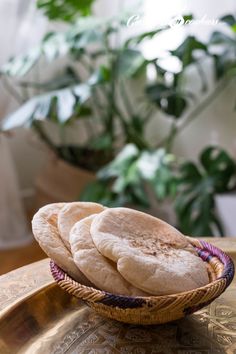 three pita breads in a wicker basket on top of a brass platter