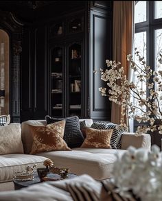 a living room filled with lots of furniture next to a tall black bookcase covered in books