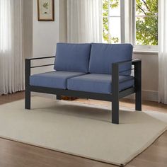 a blue couch sitting on top of a white rug in front of a large window