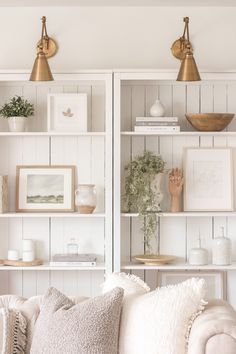 a living room filled with white furniture and lots of shelves covered in bookshelves