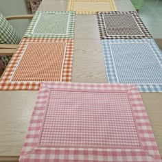 four different colored placemats sitting on top of a wooden table with green cabinets in the background