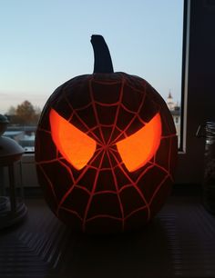 a spiderman pumpkin with glowing eyes is sitting on a window sill in front of a window