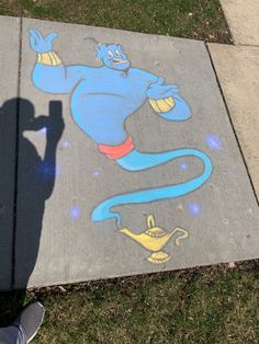 a person standing in front of a sidewalk with chalk drawings on it and the shadow of a person holding a cell phone