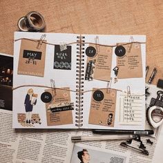 an open planner book with clothes pins and magnets attached to it, on top of a newspaper