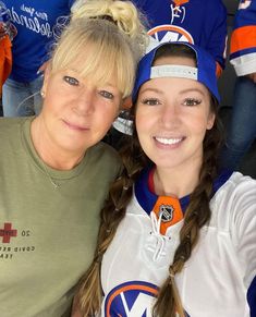 two women are posing for a photo in front of an ice hockey team with their arms around each other