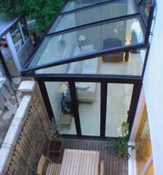 an aerial view of a house with glass walls and wood flooring, looking down on the patio