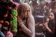 a woman standing next to a pile of stuffed animals