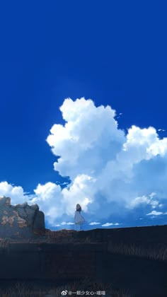 a person standing on top of a hill under a blue sky with clouds in the background