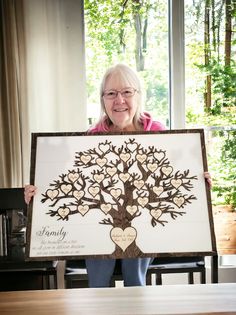 an older woman holding up a family tree with hearts on it and the words, we are