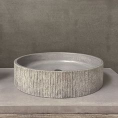 a round concrete sink sitting on top of a counter next to a wall mounted faucet