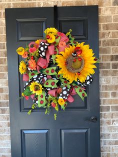 a black front door with a sunflower wreath and polka dot bow on the side