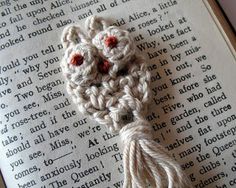 an old book with a crocheted tassel on top of it and a red eyeball in the middle