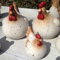 four ceramic chickens sitting on top of a wooden table